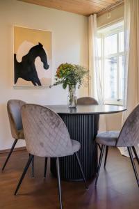 ein Esszimmer mit einem Tisch und Stühlen sowie einer Vase mit Blumen in der Unterkunft Charming and bright apartment in Ålesund city in Ålesund