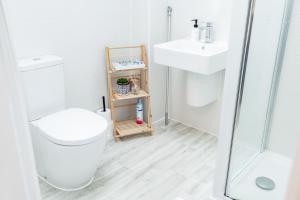a white bathroom with a toilet and a sink at Beautifully Fab 3 bedroom 4 beds New home 8 guests Stretford Trafford in Manchester +25 photos