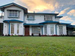 a white house with a large yard at Aaradhya Nuwara Eliya in Nuwara Eliya +51 photos