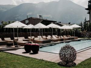 a swimming pool with lounge chairs and umbrellas at Boutique Hotel Haidachhof superior in Fügen