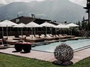 a swimming pool with lounge chairs and umbrellas at Boutique Hotel Haidachhof superior in Fügen