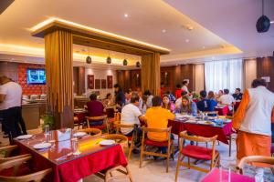 a group of people sitting at tables in a restaurant at HOTEL NILADRI PREMIUM in Puri