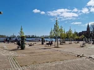 a park with people sitting on benches near the water at FeWo Varis in Röbel