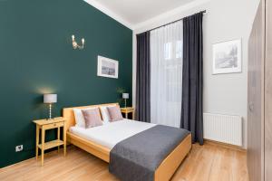 a bedroom with a bed with blue walls and a window at Miodowa Boutique Residence in Krakow