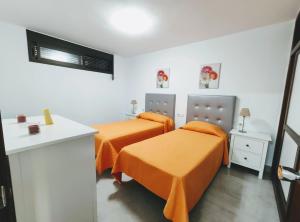 two beds with orange sheets in a room at Casa Royal Los Cristianos Center in Los Cristianos