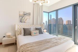 1 dormitorio con cama blanca y ventana grande en HiGuests - High Level Luxury Apartment With Marina Views, en Dubái