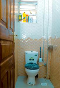 a bathroom with a toilet with a blue seat at Tashma Airbnb Apartment in Nairobi