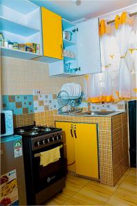 a small kitchen with a stove and yellow cabinets at Tashma Airbnb Apartment in Nairobi