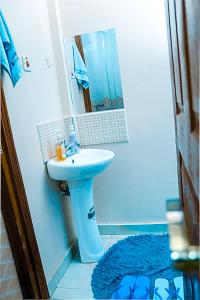 a bathroom with a blue sink and a mirror at Tashma Airbnb Apartment in Nairobi