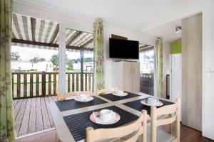 a dining room with a table and chairs and a balcony at Bungalow T3 I - 15 Min From Nazaré in Pataias