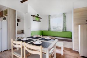 uma sala de jantar com uma mesa e um sofá verde em Bungalow T3 I - 15 Min From Nazaré em Pataias