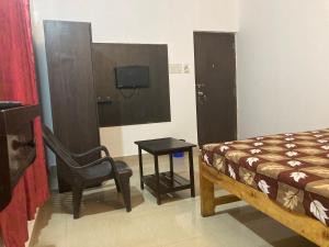a bedroom with a bed and a chair and a tv at Hotel Khushi Waves in Arpora