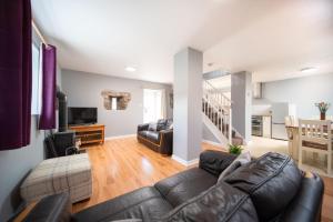 a living room with a leather couch and a table at Duror Cottage at Lower Aylescott in West Down