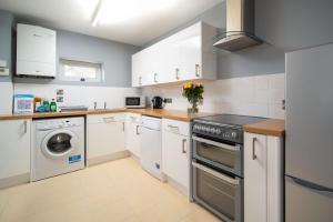 a kitchen with white cabinets and a stove at Duror Cottage at Lower Aylescott in West Down