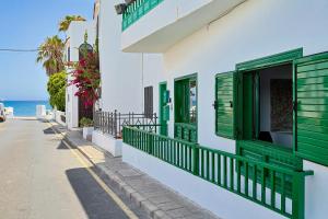 a building with green shuttered windows and a street at Luxury Beach Sea Front Guanarame in Playa Honda