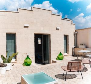 eine Terrasse mit grünen Vasen, Tischen und Stühlen in der Unterkunft Le Vie Del Centro Luxury Room in Matera