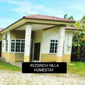 ein kleines Haus mit einem Schild davor in der Unterkunft Rezqrich Villa Homestay 1 in Kampung Degong