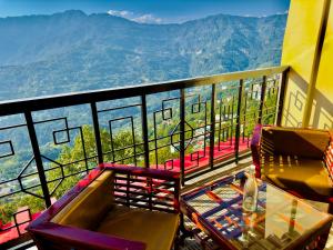 a table and chairs on a balcony with a view of mountains at Tara Palace Resort and SPA in Gangtok