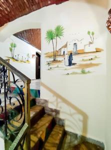 a staircase with a mural of palm trees on the wall at Hadouta Masreya Nubian Guest House in Aswan