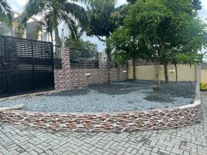 einen Zaun mit einem Baum vor einem Gebäude in der Unterkunft Coolzzy GM247 Homes-Accra Kwabenya Villas in Accra