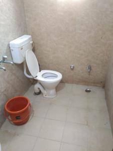 a bathroom with a toilet and a bucket in it at Agarwal Guest House in Naya Raipur