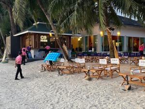 Un homme se promène sur une plage avec des chaises et des tables. dans l'établissement Coconut Beach Resort, Koh Chang, à Ko Chang