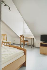 a bedroom with a bed and two chairs and a tv at Gasthof Kirchberger in Fürth