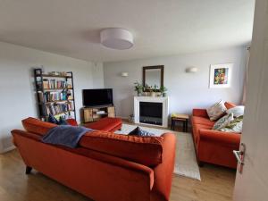 salon z 2 pomarańczowymi kanapami i telewizorem w obiekcie Modern 2 bedroom home with ample parking w mieście Henwick