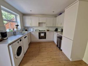kuchnia z białymi szafkami i drewnianą podłogą w obiekcie Modern 2 bedroom home with ample parking w mieście Henwick
