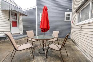 Una mesa con sillas y una sombrilla roja en un patio. en Charming Guest House - Pittsburgh's Little Italy, en Pittsburgh