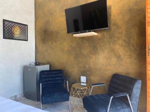 um quarto com duas cadeiras e uma televisão na parede em Suite Boutique Lodge em Pretoria