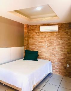 uma cama num quarto com uma parede de tijolos em DOM POUSADA em São Gonçalo do Amarante