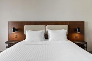a large bed with two white pillows and two chairs at Courtyard by Marriott Munich City East in Munich