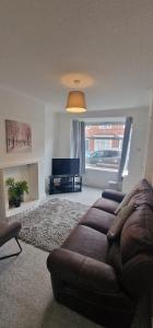 a living room with a brown couch and a television at Cosy Fresh New Refurbished House in Doncaster