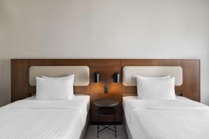 two beds with white sheets and a chair between them at Courtyard by Marriott Munich City East in Munich