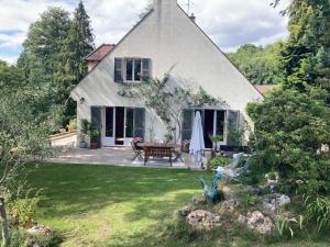 una gran casa blanca con un banco en un patio en Comme chez Vous, en Briis-sous-Forges
