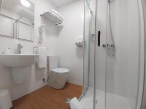 a bathroom with a shower and a toilet and a sink at Hotel Santiago Vagos in Ílhavo