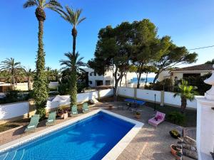 uma piscina com palmeiras e uma villa em Chalet Villa Mediterránea a 75 metros de la playa. em Orihuela