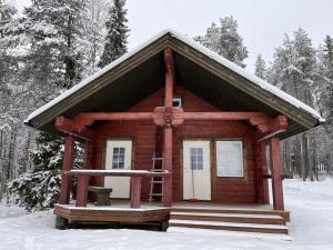 una pequeña cabaña de madera en la nieve con árboles en Kenttäniemi Cottages en Sonka