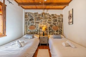 two beds in a room with a stone wall at Casa rural a pie de Sierra Nigüelas in Nigüelas +23 photos