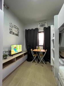 Zimmer mit einem Tisch, einem TV und einem Bett in der Unterkunft Iza's Studio Apartment in Manila