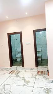 two mirrors in a bathroom with sinks and toilets at Hotel Shri Krishna Palace in Ujjain