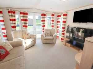 a living room with couches and a flat screen tv at No 35 Meadows Retreat Lodge Park in Cockermouth