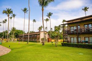 a building with palm trees in front of a park at Grand Oca Maragogi All Inclusive Resort in Maragogi