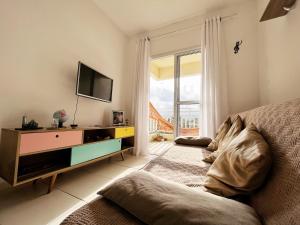 ein Wohnzimmer mit einem TV und einem Sofa in der Unterkunft Confortável apartamento perto de praias - Bertioga in Bertioga