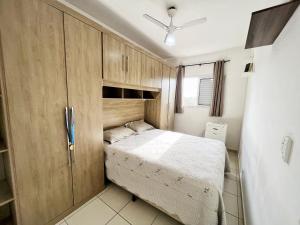a small bedroom with a bed and wooden cabinets at Confortável apartamento perto de praias - Bertioga in Bertioga +74 photos