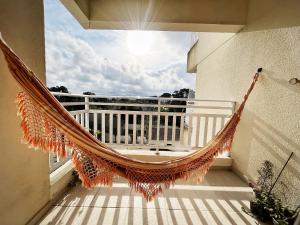 a hammock on a balcony with a view of the sky at Confortável apartamento perto de praias - Bertioga in Bertioga