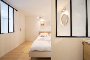 Habitación blanca con cama y espejo en 3. charmant appartement proche centre et gare, en Valence