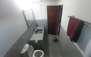 La salle de bains est pourvue d'un lavabo, de toilettes et d'un miroir. dans l'établissement Oronner Din Ratri, à Sreemangal