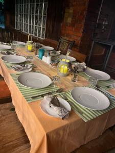 una mesa larga con platos y servilletas. en Zamani za kale en Kabuku